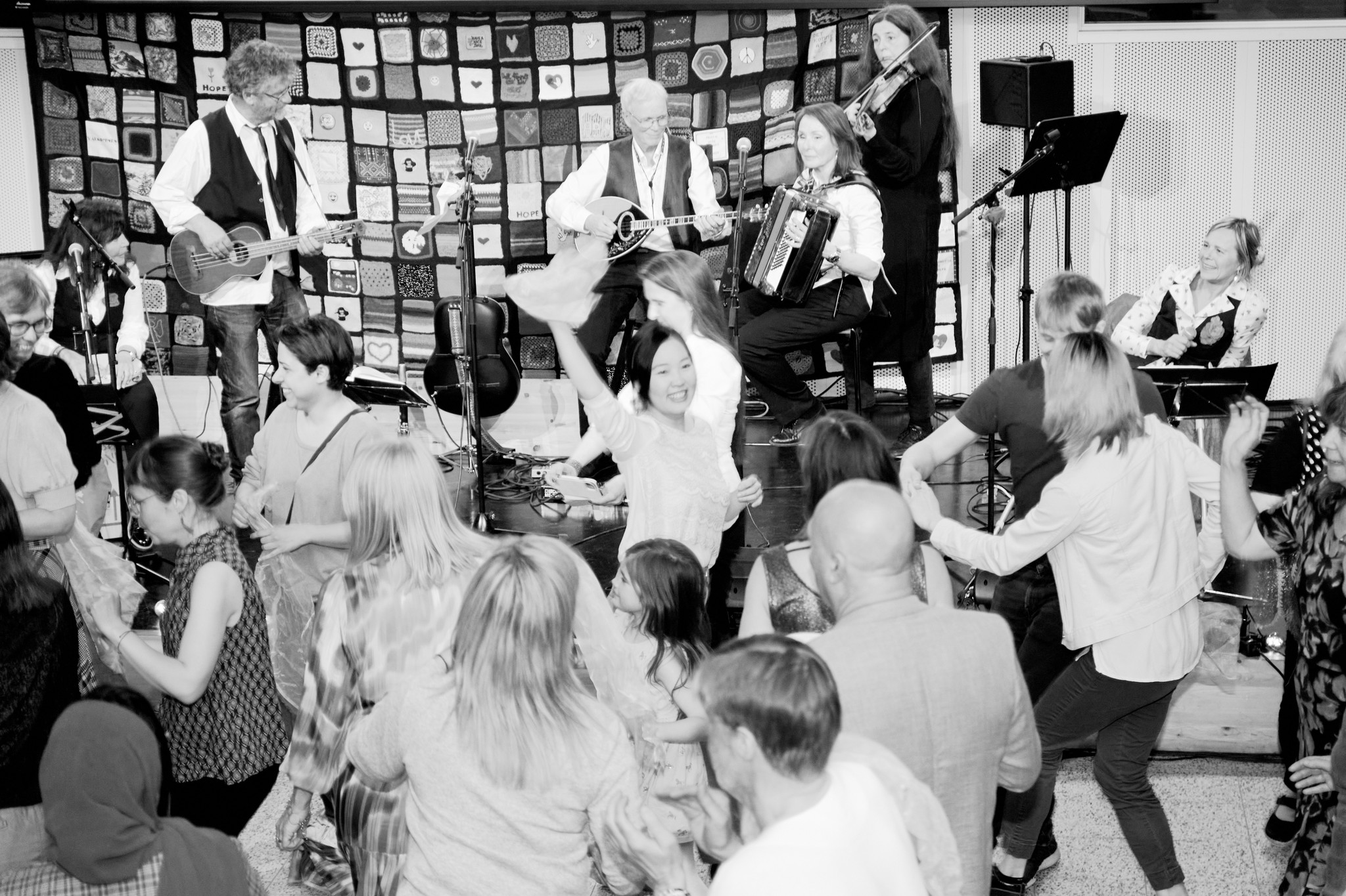 En svartvit bild på massa glada människor som spelar musik och dansar