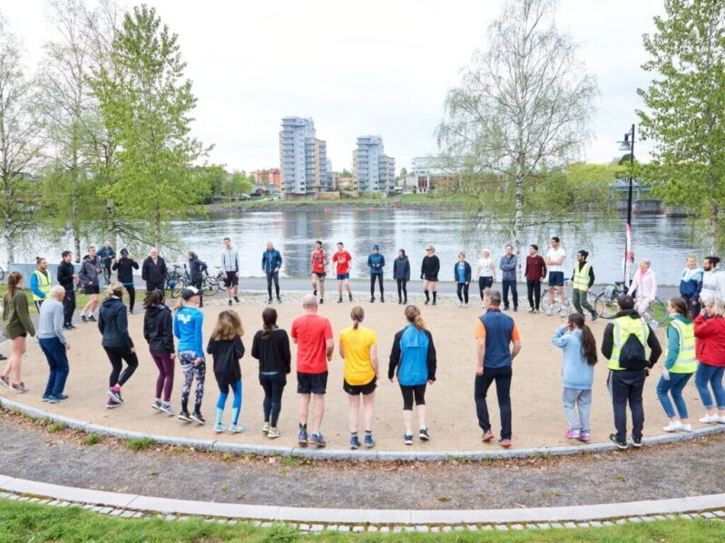 Ungefär 30 personer som värmer upp tillsammans i Broparken innan parkrun