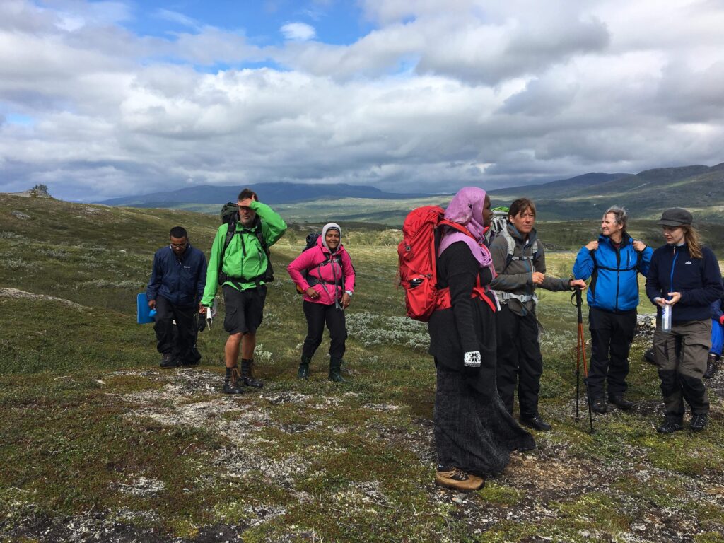 Bild på människor med olika nationaliteter som fjällvandrar i Hemavan. Alla har ryggsäckar på sig.