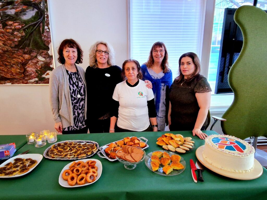 5 kvinnor står bakom ett bord fullt av fikabröd från olika länder